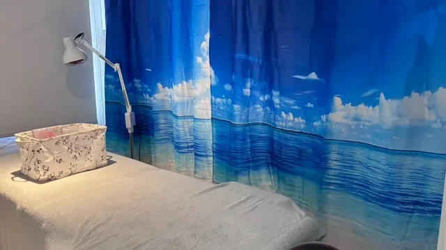 Bedroom with ocean and sky mural curtains, bed, and decorative pillow