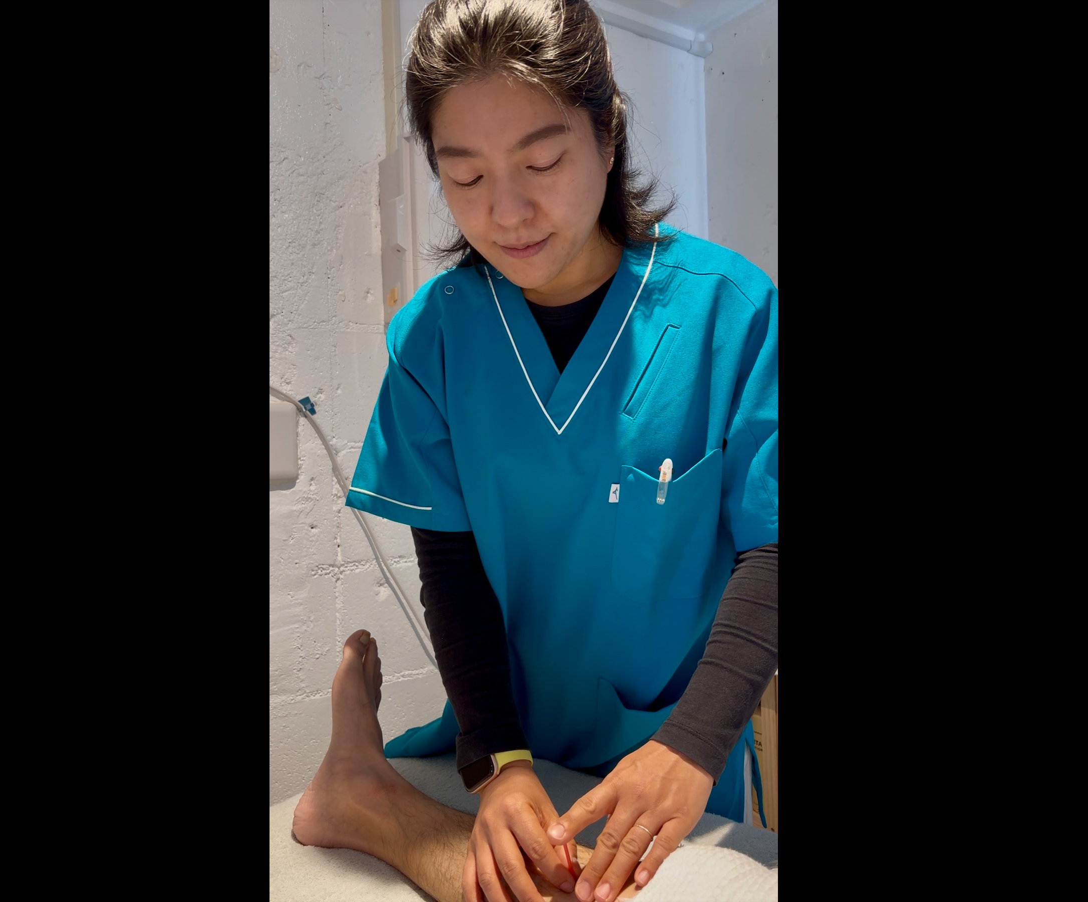 Healthcare professional in blue scrubs examining a patient's foot or ankle